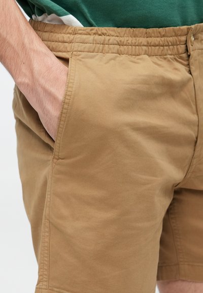 Shorts bej din bumbac, cu talie elastică și buzunare laterale. Textură netedă, cu detalii de cusătură vizibile.