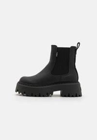 Bottines noires avec une finition en cuir texturé, des panneaux latéraux élastiques, une semelle plateforme épaisse et une semelle en caoutchouc striée pour plus d'adhérence.