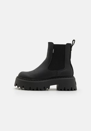 Bottines noires avec une finition en cuir texturé, des panneaux latéraux élastiques, une semelle plateforme épaisse et une semelle en caoutchouc striée pour plus d'adhérence.