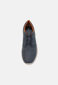 Chaussure en cuir bleu marine avec une surface texturée, bout rond, à lacets à l'avant et doublure orange. Taille 42 imprimée à l'intérieur. Semelle de couleur claire.