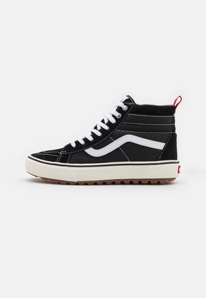 Zapatilla alta negra con acentos blancos, que presenta una parte superior de ante texturizado, costuras en contraste y una suela de goma con una banda de rodadura marrón.