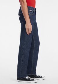Jeanși din denim albastru închis, cu un croi drept, având un design clasic cu cinci buzunare și un mic patch cu logo pe buzunarul din spate.
