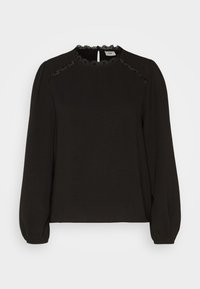 Blouse noire à manches longues avec bordure en dentelle sur les épaules et le col, fermeture à boutonnière à l'encolure et poignets froncés.