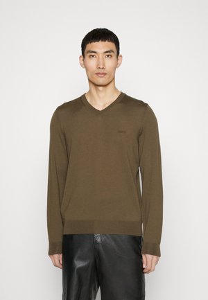 Pull en v en khaki en maille douce, avec des manches longues et des accents en côte subtils aux poignets et à l'ourlet. Branding minimal sur la poitrine.