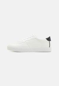 Hvite sneakers med overdel i glatt lær, med perforerte detaljer, runde snørebånd og svart aksent på hælen. Gummisåle.