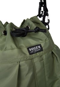 Green nylon bucket bag with a drawstring top, black hardware, and a logo patch. Features pleated design and durable fabric texture.