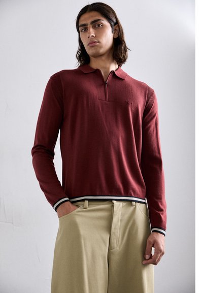 Polo shirt rosso lavorato a maglia con mezza zip, texture a coste sulle spalle e strisce nere e bianche a contrasto sui polsini e sull'orlo.
