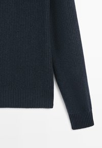Donkerblauwe gebreide trui met een gestructureerd oppervlak, voorzien van geribbelde mouwen en zoom. De stof lijkt zacht en warm, ontworpen voor comfort.