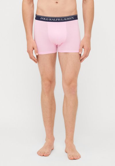 Svetlo roza bokserice z mornarsko modrim pasom, ki nosi logotip "POLO RALPH LAUREN". Mehka tkanina, prilegajoča zasnova in dolžina do sredine stegna.