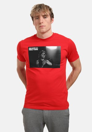 Rød bomulds t-shirt med et sort-hvidt grafisk tryk af en karakter fra "Escape from New York" med tekst over billedet.