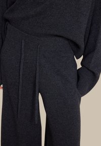 Mørkegrå strikkegenser og matchende vide bukser med strikk i livet. Glatt tekstur, oversized passform og ribbestrikkede mansjetter.