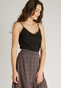 Camisole noir avec dentelle, associé à une jupe à imprimé floral avec des fleurs roses et blanches sur un fond sombre, ourlet léger.