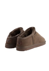 Bruine suède pantoffels met een zachte, textuurrijke binnenvoering, laag profiel ontwerp en een merkembleem op de hiel. Flexibele rubberen zool.