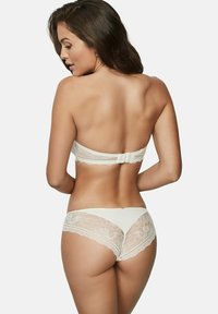 Ensemble de lingerie en dentelle blanche comprenant un soutien-gorge de style bandeau avec fermeture à crochets et des panties assorties avec des détails en dentelle florale.