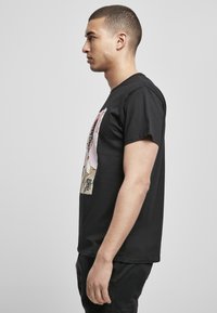 Black cotton t-shirt featuring a large front graphic print. Short sleeves, crew neck, and relaxed fit, showcasing a smooth texture.