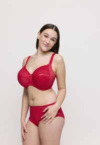 Bra rosso con pizzo e mutandine a vita alta coordinate, caratterizzati da un tessuto morbido, spalline regolabili e una forma arrotondata.