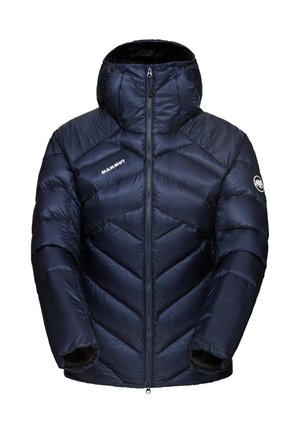 Veste matelassée bleu marine avec un col montant, un motif de serpentin, et des manches longues. Présente une fermeture éclair à l'avant et des accents de logo sur la manche.