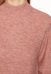 Ljusrosa ribbad stickad tröja med hög halsringning, med en mjuk textur och en figurnära design. Inga synliga mönster eller detaljer.