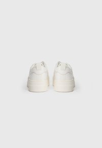 Witte sneakers met een glad leren bovenkant, een gevoerde kraag en een verhoogde rubberen zool. Voorzien van een lus op de hak voor gemakkelijk aan- en uittrekken.