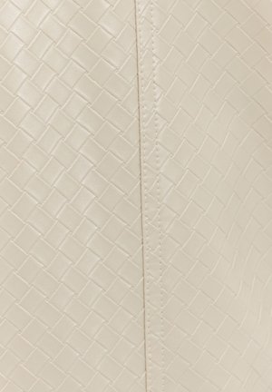 Texture en cuir tissé de couleur crème avec une couture verticale au centre, mettant en valeur le détail de l'artisanat.