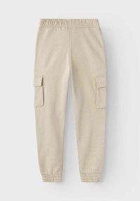 Pantalones jogger beige, confeccionados en tela suave, con cinturilla elástica, tobillos acampanados y dos bolsillos laterales tipo cargo con solapas.