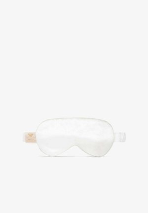Jedwabna maska do spania w kolorze białym, o gładkiej fakturze i wyprofilowanym kształcie. Posiada regulowany pasek oraz małą metkę z logo po jednej stronie.