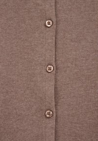 Braun gerippter Cardigan-Stoff mit vier runden, hellbraunen Knöpfen, die jeweils vier Löcher haben und ein strukturiertes, schichtartiges Erscheinungsbild bieten.