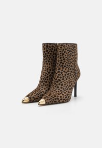 Bottes au motif léopard, fabriquées en tissu texturé avec un bout pointu et des accents dorés à la pointe, présentant un talon haut et fin.