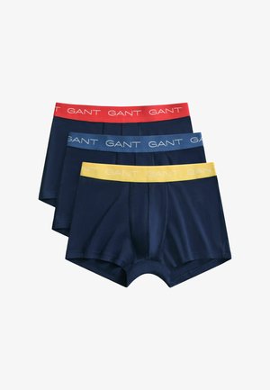 Trois boxers bleus marine empilés, chacun avec une ceinture de couleur différente : rouge, bleue et jaune, toutes marquées du texte "GANT".