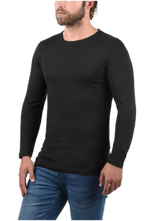 Black long-sleeve t-shirt made of soft cotton. Features a crew neck, fitted design, and smooth texture. Paired with blue denim jeans.