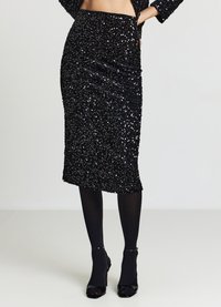 Schwarzer Pailletten-Bleistiftrock mit Raffung, knielang, strukturierte Oberfläche, kombiniert mit schwarzen Strumpfhosen und High Heels, mit figurbetonter Silhouette.