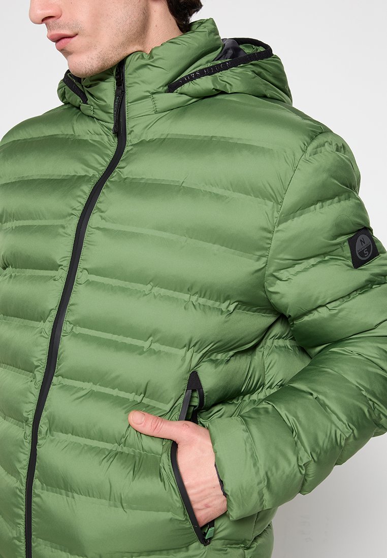 Giacca a vento verde con pannelli trapuntati orizzontali, chiusura con zip frontale e cappuccio. Dettagli in zip e accenti neri completano il design.