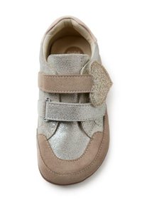 Zapatilla de deporte beige y plateada para niño, con dos correas ajustables de gancho y bucle y cuello acolchado, vista desde arriba sobre un fondo blanco.