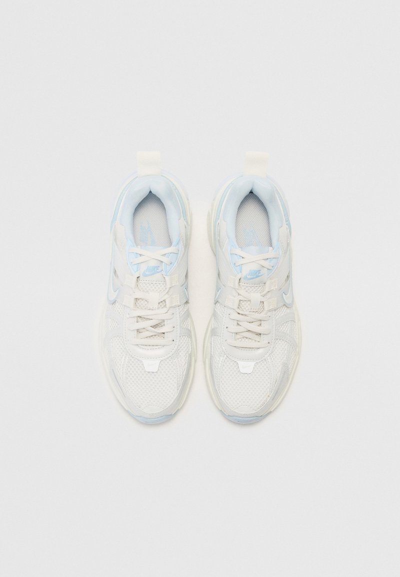 Zapatillas deportivas blancas y azul claro con parte superior de malla, cierre de cordones, cuello acolchado y suela texturizada que presenta un detalle de logo.