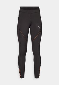 Černé sportovní legíny s vysokým pasem, síťovinovými detaily a křižuj�ícími výřezy na dolních nohavicích. Na legínách je malé logo Puma.