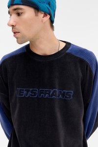 Sweatshirt de cordura preto com mangas em azul canelado. "LETS FRANS" bordado em azul na parte da frente. Gola redonda, tecido texturizado.