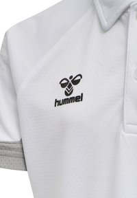 Witte polo met textuurstof, grijze accenten op de mouwen en een zwart logo geborduurd op het linkerborstgebied.