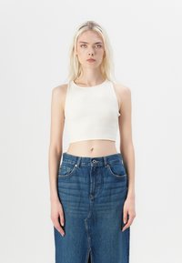 White ribbed cropped tank top with a round neckline paired with high-waisted blue denim skirt featuring a front slit and classic five-pocket design.
