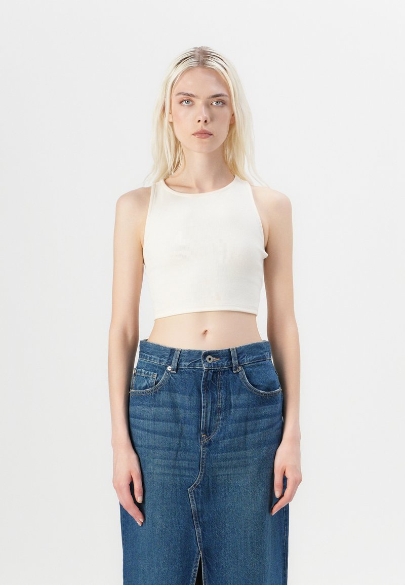 White ribbed cropped tank top with a round neckline paired with high-waisted blue denim skirt featuring a front slit and classic five-pocket design.