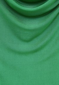 Tissu léger vert à la texture lisse, présentant des plis drapés. Le matériau semble extensible et de couleur uniforme.