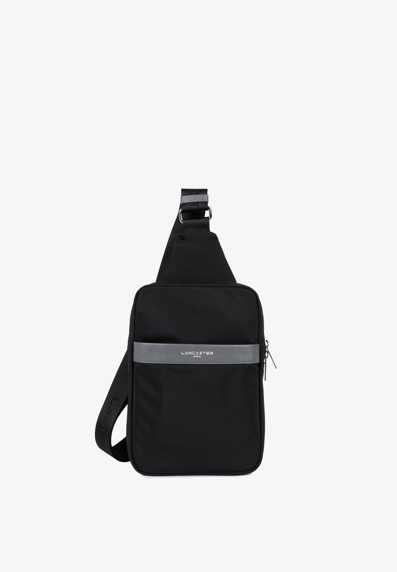 Sac à bandoulière noir en tissu lisse et durable. Dispose d'une poche zippée sur le devant, d'une bande d'accent grise et d'une bandoulière ajustable pour plus de confort.