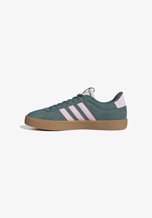 Zapatilla baja de ante en color azul verdoso con rayas y lengüeta en rosa, suela de goma y cordones en azul verdoso oscuro, mostrada en perfil lateral.
