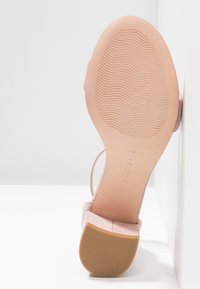 Escarpin à talon aiguille en daim rose avec une semelle intérieure lisse, une semelle extérieure texturée et un design minimaliste. Marque de la marque visible sous le talon.