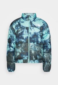 Chaqueta tipo puffer en teñido de azul y negro, con cremallera frontal, bolsillos laterales, cuello alto y el logo de The North Face en el pecho.