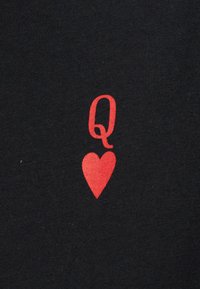 Symbole de la Reine de Cœur rouge imprimé sur un tissu noir avec une texture claire visible.