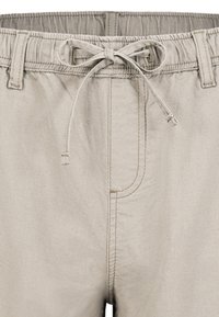 Beige Shorts mit elastischem Bund, Kordelzugverschluss und Seitentasche. Der Stoff hat eine glatte Textur und dezente Nähte.