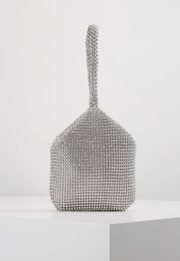 Liten strukturerad silverväska för kvällsbruk täckt av glittrande rhinestones med ett kort handtag, uppställd på en vit yta.