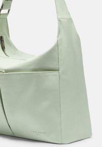 Bolso de hombro verde claro hecho de un material suave y duradero; cuenta con un cierre de cremallera, un bolsillo lateral y un logo de la marca en relieve en la parte frontal.