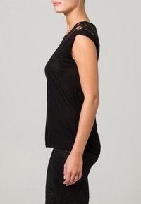 Mustapaita, jossa on pitsikoristeiset harteet, lyhyet hihat ja sileä pinta. Muotoilu on yksinkertainen ja siinä on pyöreä kaula-aukko.