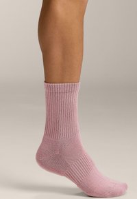 Calzini rosa a coste con design a metà polpaccio, texture liscia e aree di tallone e punta rinforzate, adatti per l'uso quotidiano.